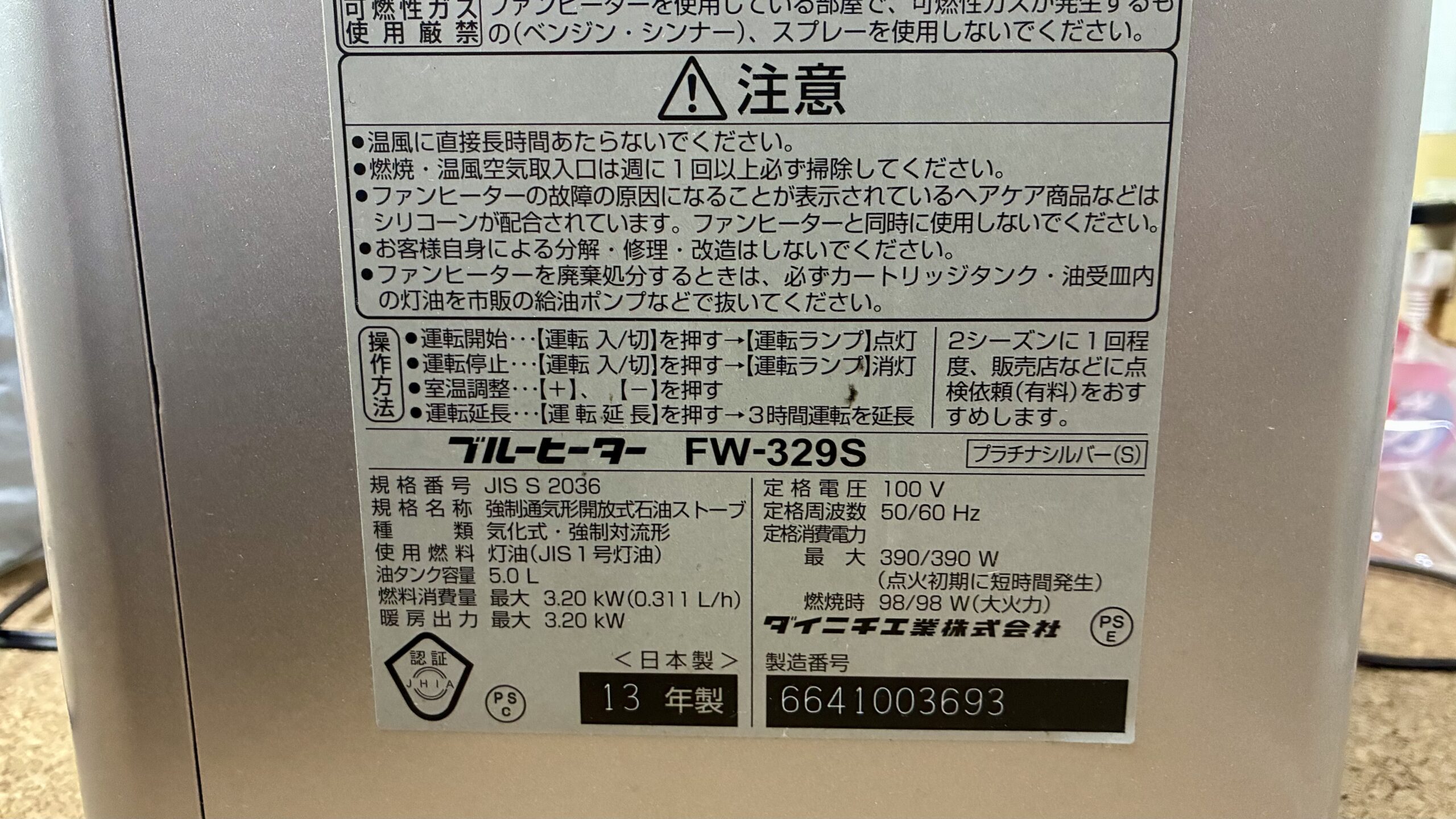 ダイニチFW-329Sの銘板。使用燃料は灯油で、点火時と燃焼時の消費電力が別に書かれている